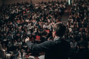 man public speaking in front of large crowd